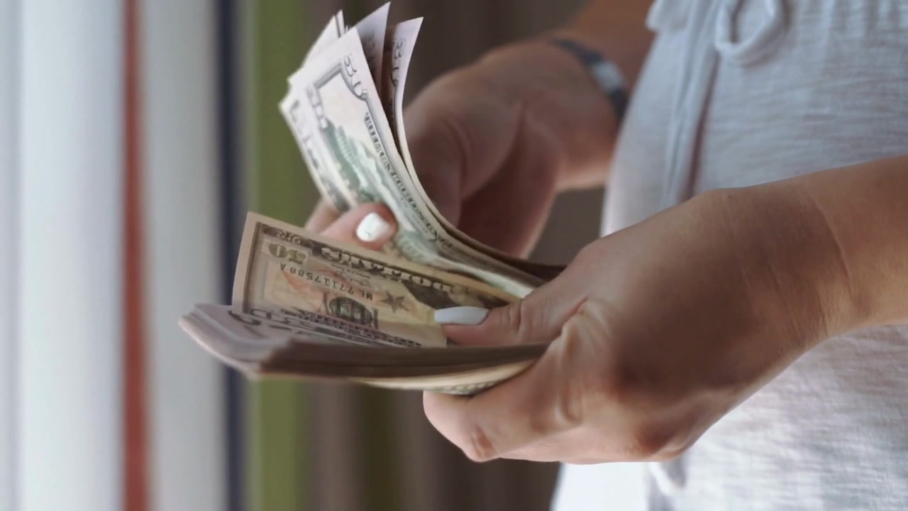 Una mujer contando billetes de dólar.