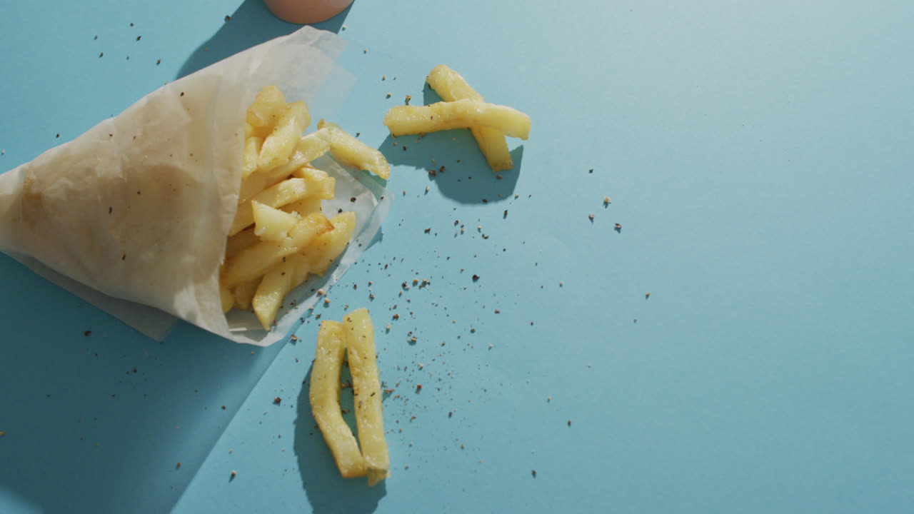 Video af pommes frites pakket ind i papir, salt og peber og dip, med plads til tekst på blå baggrund