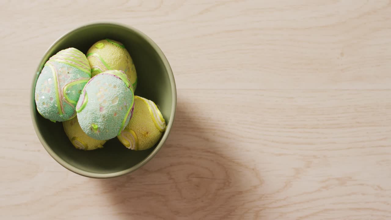 Video of decorated colorful easter eggs in bowl on a wooden surface