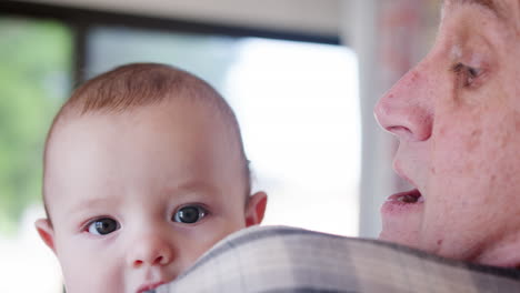 baby grandson looking over grandfathers shoulder as he cuddles him