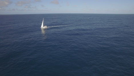 Vista-Aérea-De-Un-Yate-Blanco-En-Aguas-Azules-Del-Océano-Vacío-Contra-El-Cielo-Despejado-De-La-Isla-Mauricio