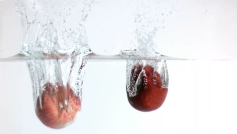 manzanas cayendo en el agua en súper cámara lenta