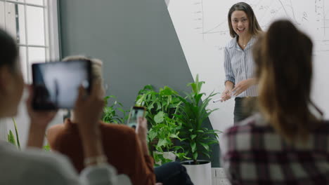 joven mujer de negocios hispana celebrando líder de equipo bailando divertido entusiasmados colegas usando tecnología móvil compartiendo la victoria corporativa en las redes sociales en una reunión de conferencias