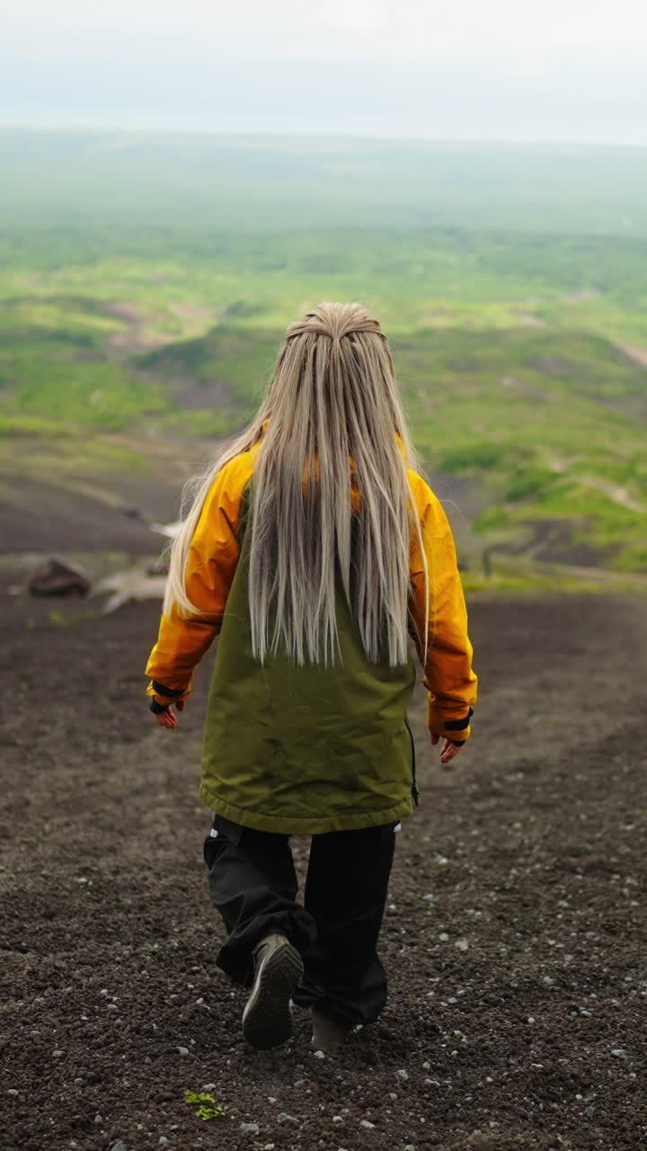 Woman with Long Blonde Hair Walking Downhill on Rocky Terrain
