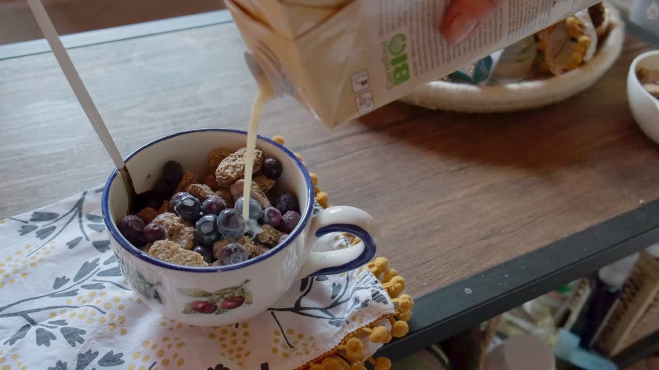 leche a base de plantas vertida sobre un tazón de cereales saludables con bayas congeladas en cámara lenta de 4k