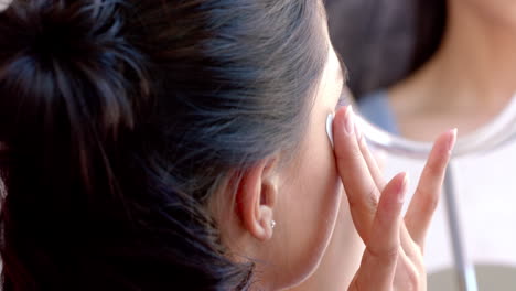 Biracial-teenage-girl-applying-under-eye-masks-looking-in-mirror,-slow-motion