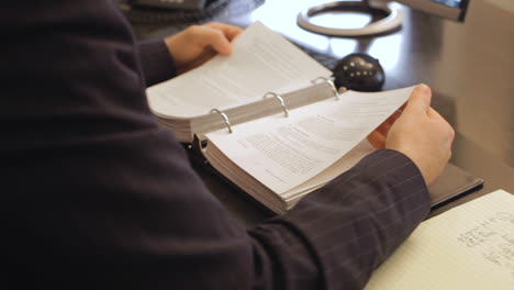 business man reading a document in a binder in his office