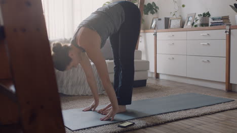 healthy yoga woman exercising at home practicing standing forward bend pose in living room enjoying morning fitness workout