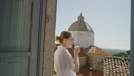 mujer usando un teléfono inteligente hermosa turista enviando mensajes de texto navegando por las redes sociales compartiendo experiencia de vacaciones disfrutando bebiendo café relajándose en el balcón mirando la vista panorámica