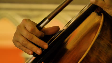 primer plano de un violonchelista masculino tocando cuerdas en un cuarteto de cuerdas en una pequeña iglesia luminosa