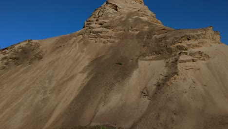 Majestic-steep-sand-dunes-against-blue-sky,-top-of-sand-dune,-rising-shot