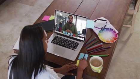 African-american-woman-writing-on-memo-notes-having-a-video-call-on-laptop-at-home