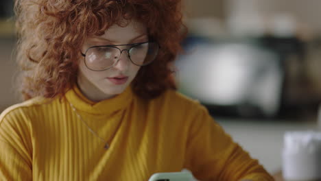 retrato hermosa joven pelirroja usando un teléfono inteligente en un café navegando en línea leyendo mensajes de redes sociales disfrutando de compartir estilo de vida en el teléfono móvil internet usando gafas