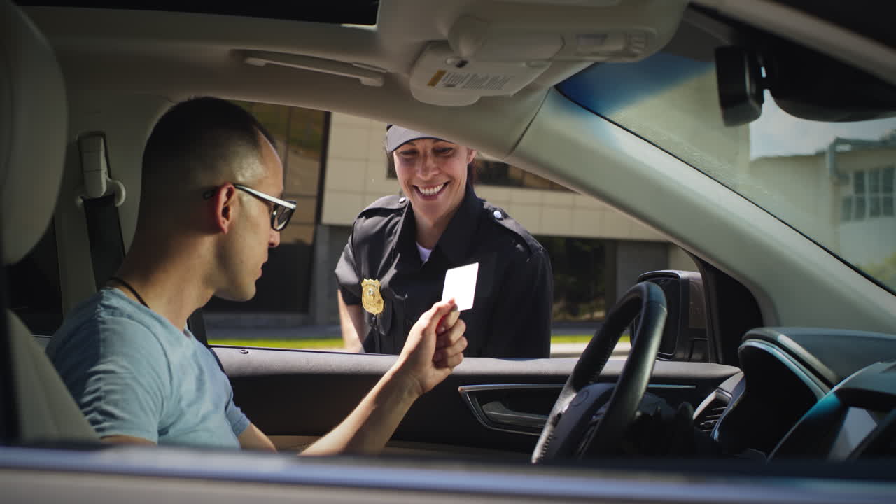friendly Police Officer Checking Digital License of Black Driver Zoom in View of Positive Woman in Police Uniform Talking with African American Man in Car and Scanning Digital Driver License on Smartphone