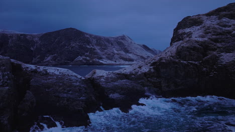 aerial shot revealing beautiful ervik behind waves crashing into ocean cliffs
