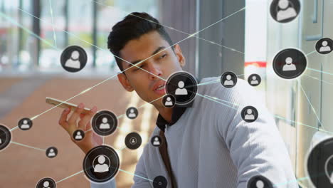 animation of network of connections with icons over biracial businessman talking on smartphone