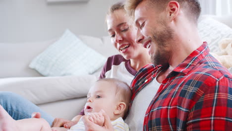 Young-white-couple-relaxing-at-home-with-their-baby