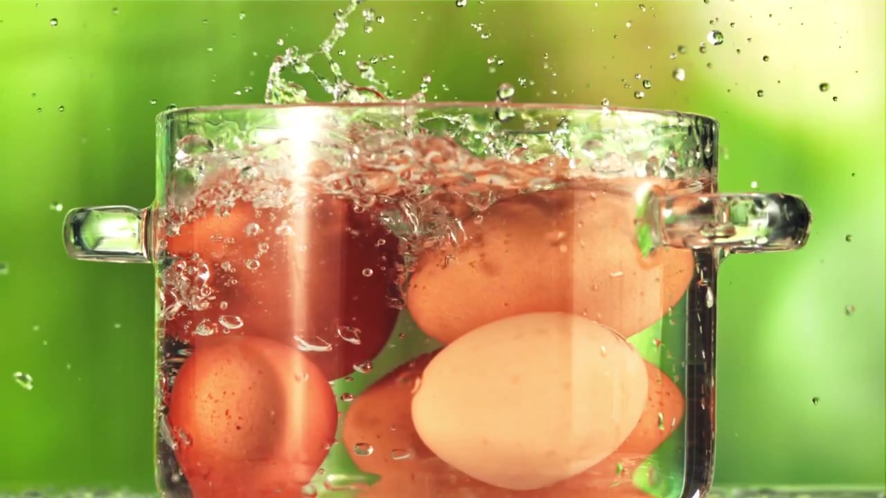 ガラスの鍋で沸騰したお湯に卵が落ちるスローモーション