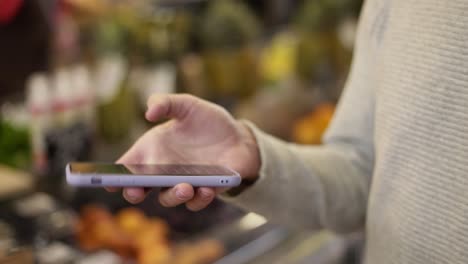 close up of a man using mobile smart phone at grocery store