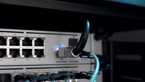 close up shot of fibre optic cable plugged in network server rack with white blinking lights