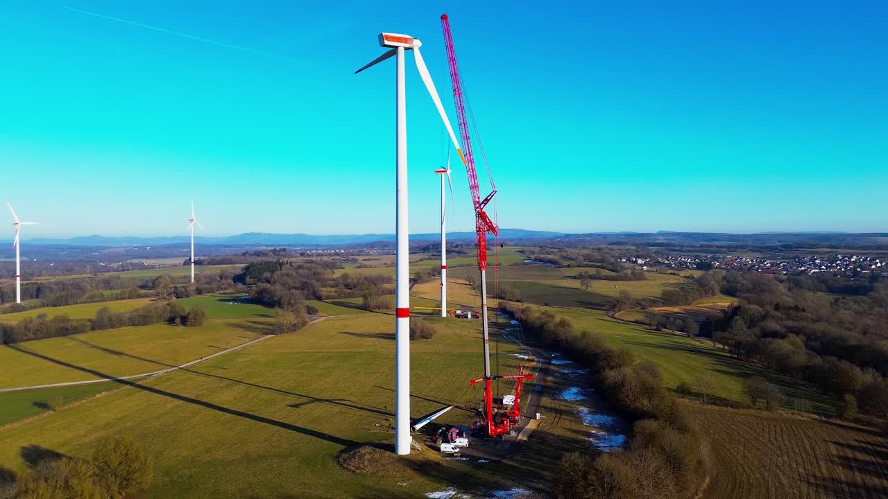 Prospettiva aerea dell'installazione di una pala di turbina eolica con gru sopra i campi rurali tedeschi