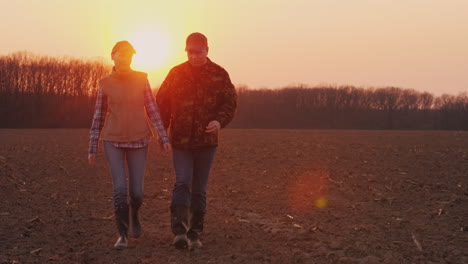 Two-Farmers-A-Man-And-A-Woman-Walking-Along-A-Plowed-Field-Talking