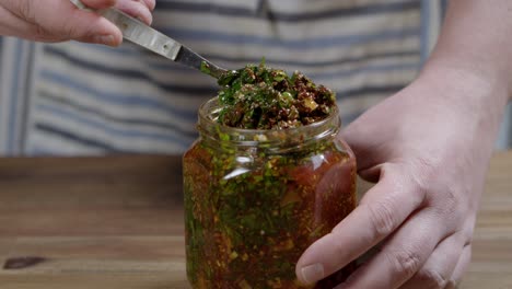 person stirring chimichurri sauce in a jar