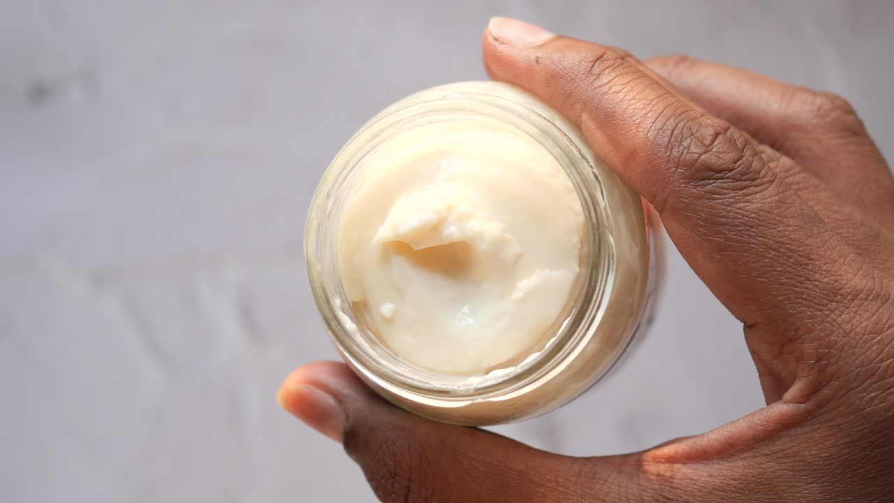 mano con un frasco de vidrio de crema