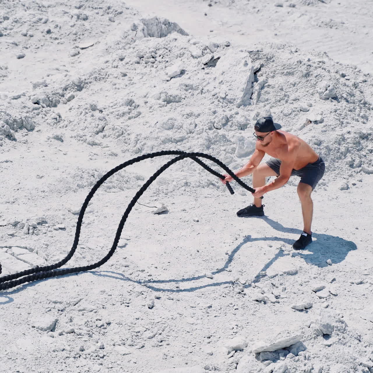 Aerial shot of a man working out with battle ropes. Bodybuilder posing outdoors.