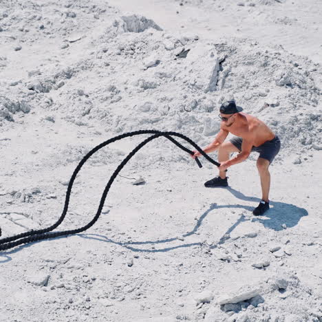 aerial shot of a man working out with battle ropes. bodybuilder posing outdoors.