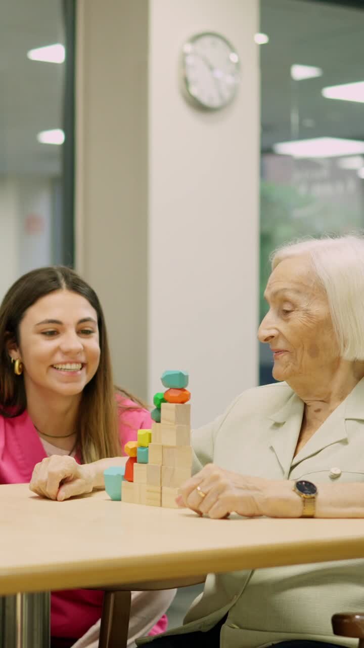 Caregiver playing with elderly woman using wooden blocks for cognitive therapy