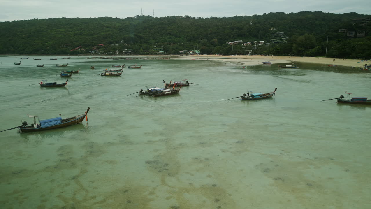 Longtail Boats Anchored in a Tropical Bay with Lush Green Hills and Beach