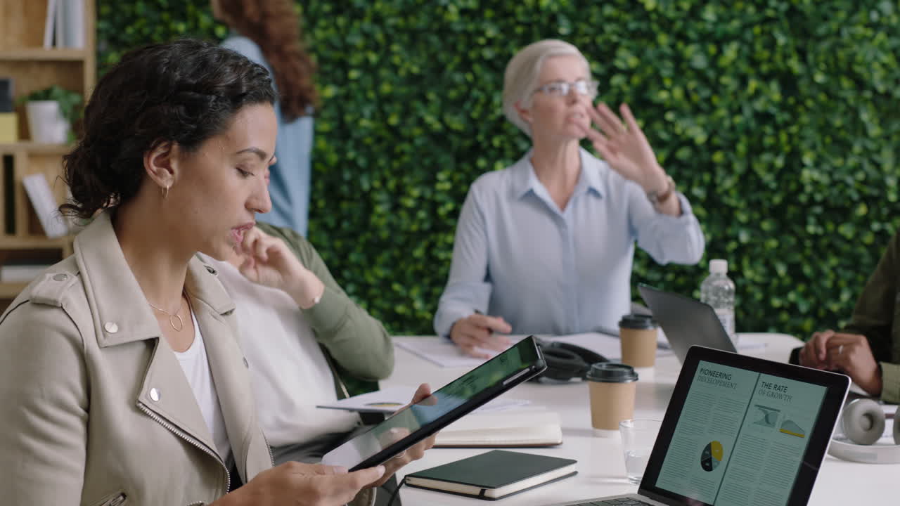 전문 사업가들이 모여 브레인스토밍을 하고 여성 리더가 금융 프로젝트에 대한 창의적인 아이디어를 공유하고 다민족 팀이 사무실 회의실에서 함께 일하고 프레젠테이션을 하고 팀워크를 즐기고 있습니다.