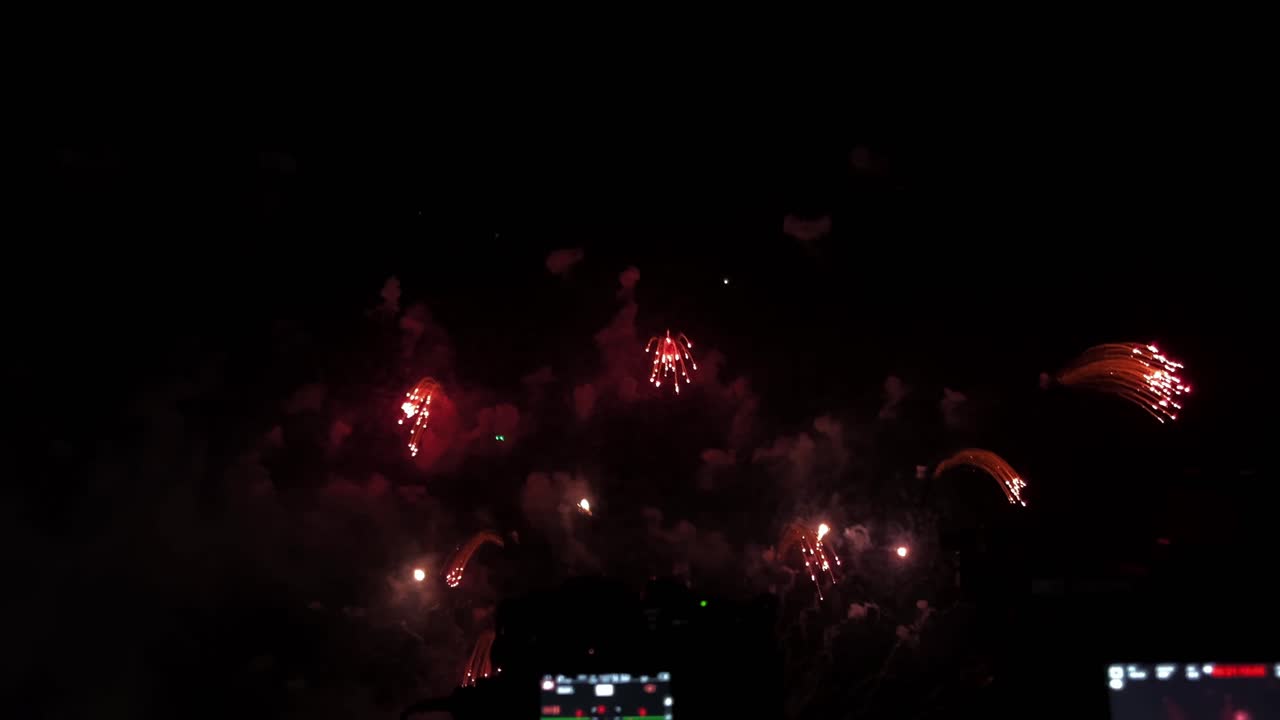 cámaras alineadas en una fila frente a una exhibición pirotécnica en una playa durante un festival de fuegos artificiales