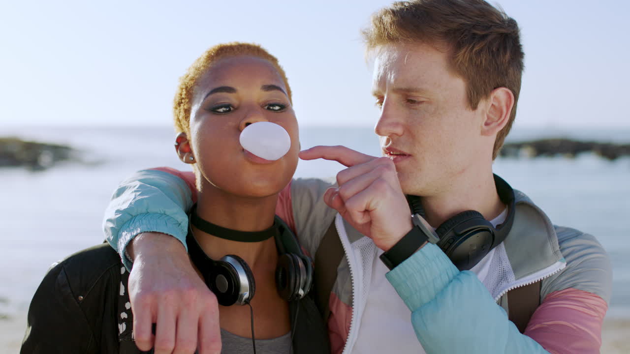 Diverse couple, beach and bubblegum with a playful