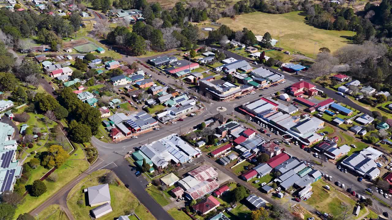 Drone ascends above Dorrigo, revealing rural town center, shops, houses, roads, and surrounding greenery