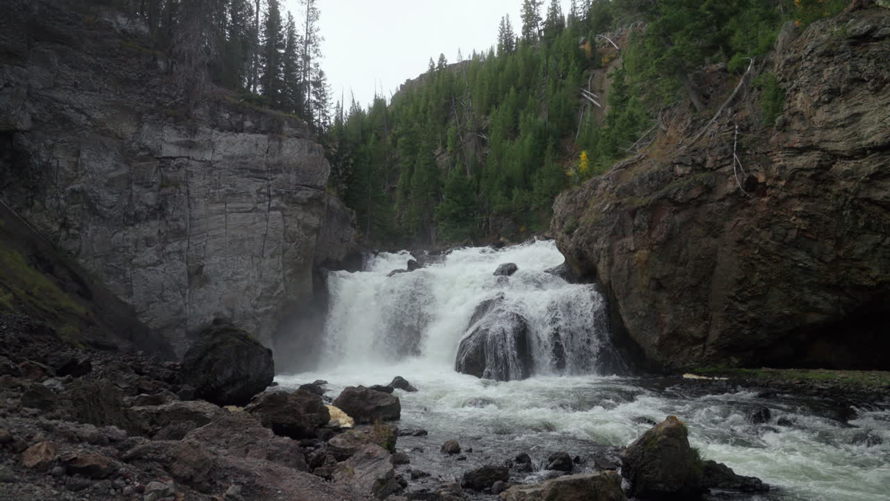 Cinematic pan down slow motion Firehole River Waterfall Canyon Drive West Yellowstone National Park Grand Loop stunning fall autumn midday October tourist view Wyoming Idaho Montana fish jumping