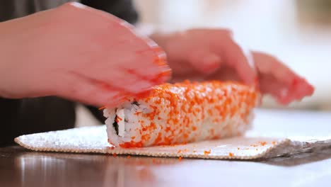 hacer sushi en la cocina de casa. manos de mujer enrollando sushi casero.