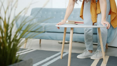 woman moving coffee table in living room