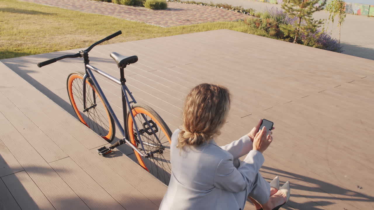 Businesswoman with Bike Using Smartphone at Waterfront