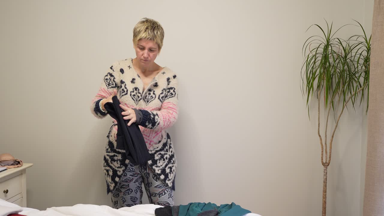 Donna che piega i vestiti in camera da letto