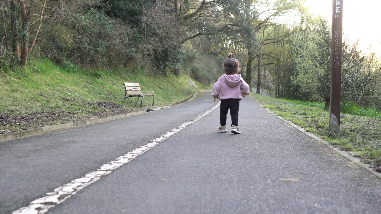 공원에서 아스팔트 트레일을 달리는 유아의 뒷모습