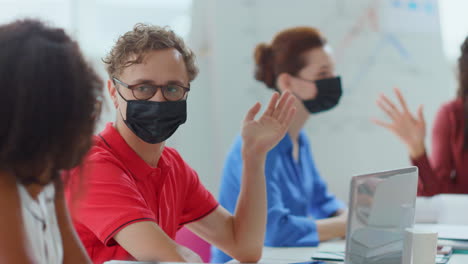 gente enmascarada trabajando en la oficina. hombre protegido hablando con colegas.