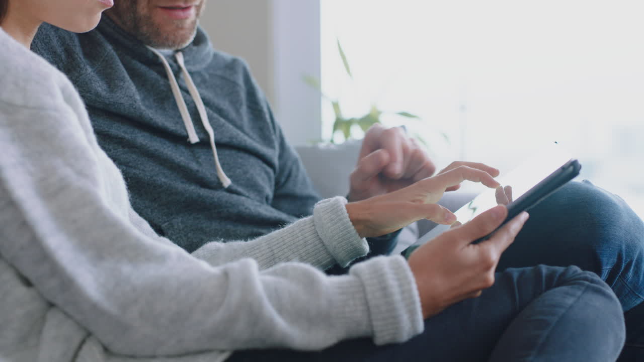 pareja feliz relajándose en casa usando el teléfono inteligente juntos comprando en línea disfrutando de navegar por internet relajándose en el sofá