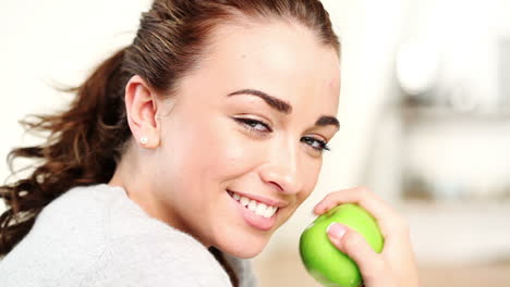 mujer joven comiendo manzana verde