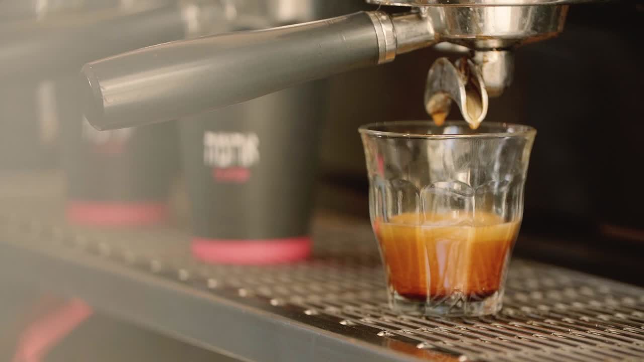 Slow-motion close-up of coffee pouring into a glass cup, capturing rich crema, smooth flow, and artisanal espresso preparation