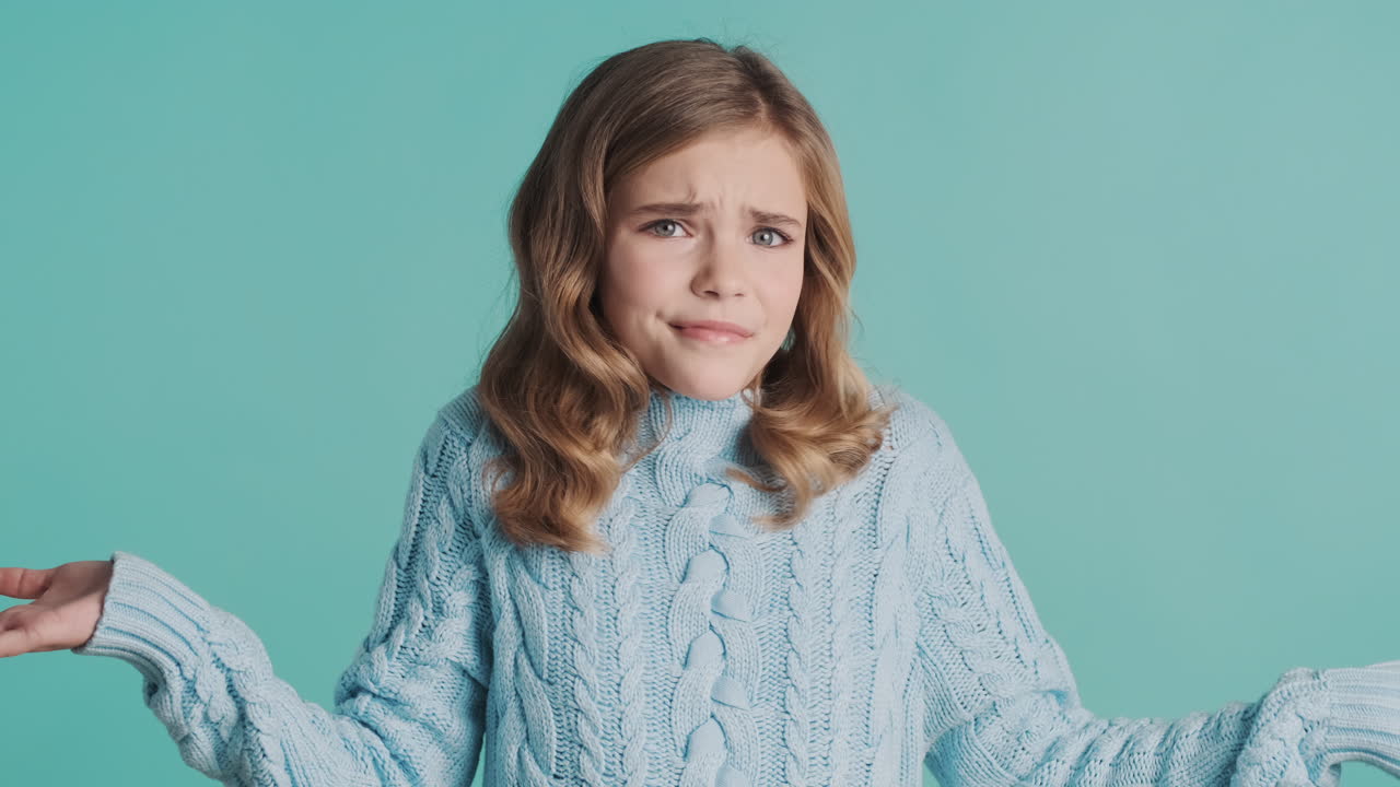 Teenage Caucasian girl shrunging shoulders at the camera.