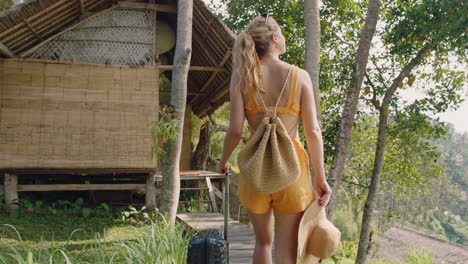 travel-woman-with-trolly-bag-arriving-at-tropical-hotel-resort-on-exotic-summer-vacation-walking-to-cottage