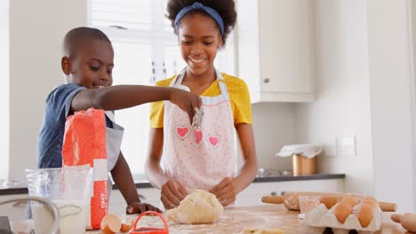 vista frontal de hermanos negros felices horneando galletas en la cocina de una casa cómoda 4k