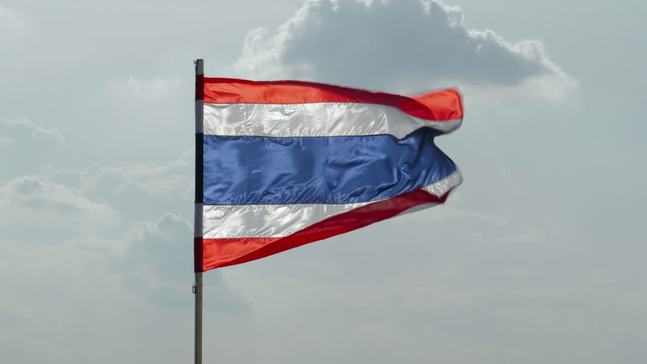 Close-up footage of the national flag of Thailand, known as the Tricolor or Thong Trairong, waving proudly in the wind. Symbol of Thai identity, patriotism, and national pride